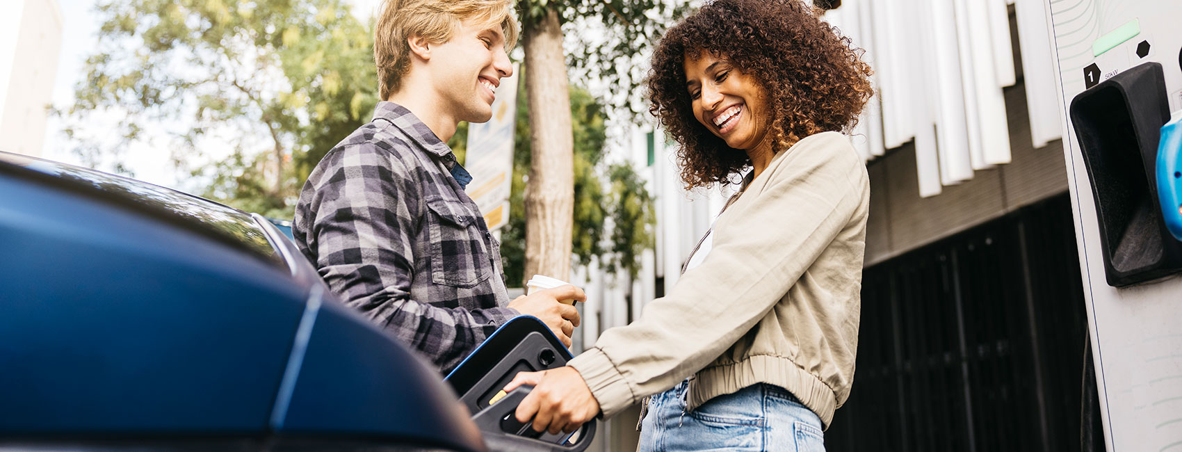 Young couple charging electric car at a city station