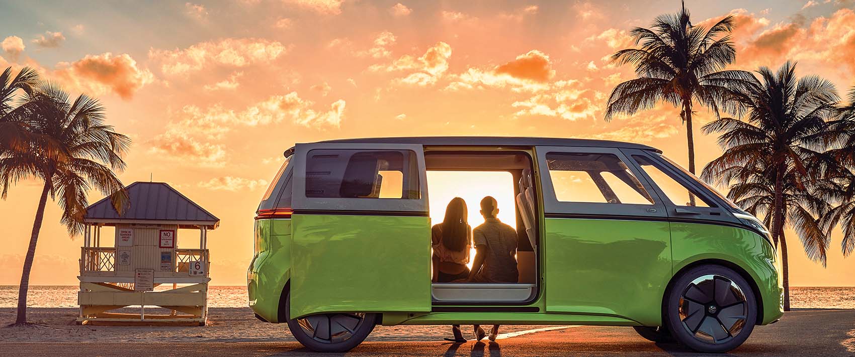 couple sitting in EV VW enjoying sunset