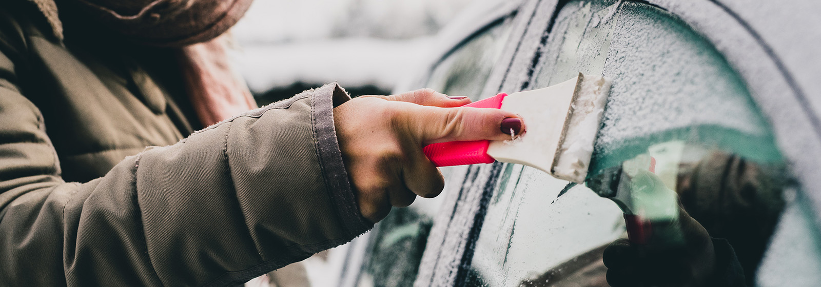 woman scraping ice off of car window