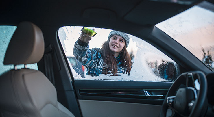 Woman scraping frost and snow from drivers side car window