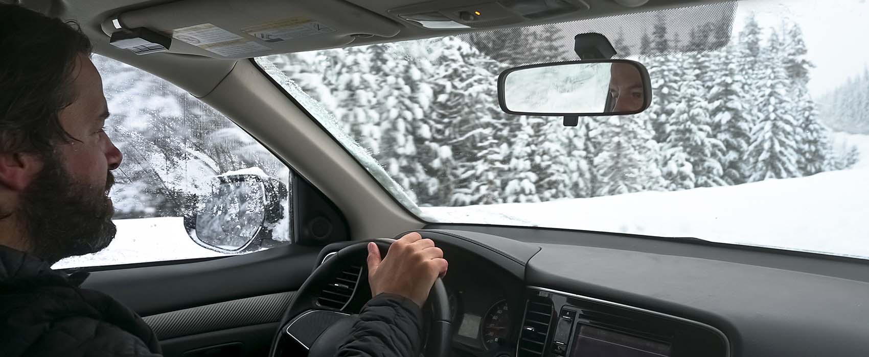 Man driving car through snowy forested road