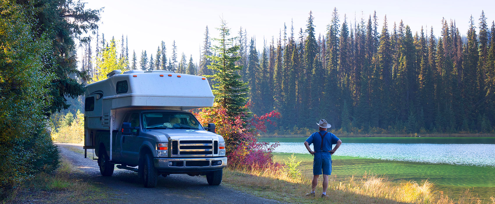 Senior man enjoying a lake with parked camper truck