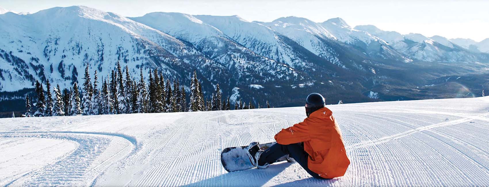 Snowboarding man sitting on sunny ski hill