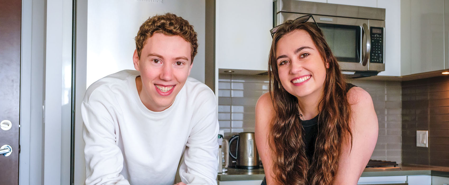 Friends Keaton Lawlor and Cassidy Cooper lean on their kitchen countertop