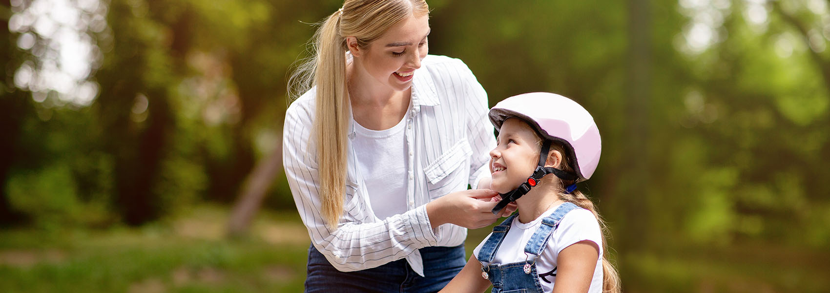 mother putting biking helmet on daughter