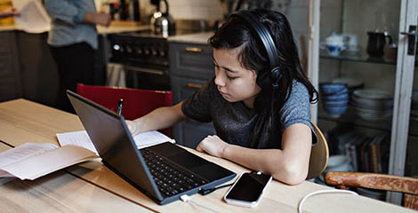 kid wearing headphones and working with laptop