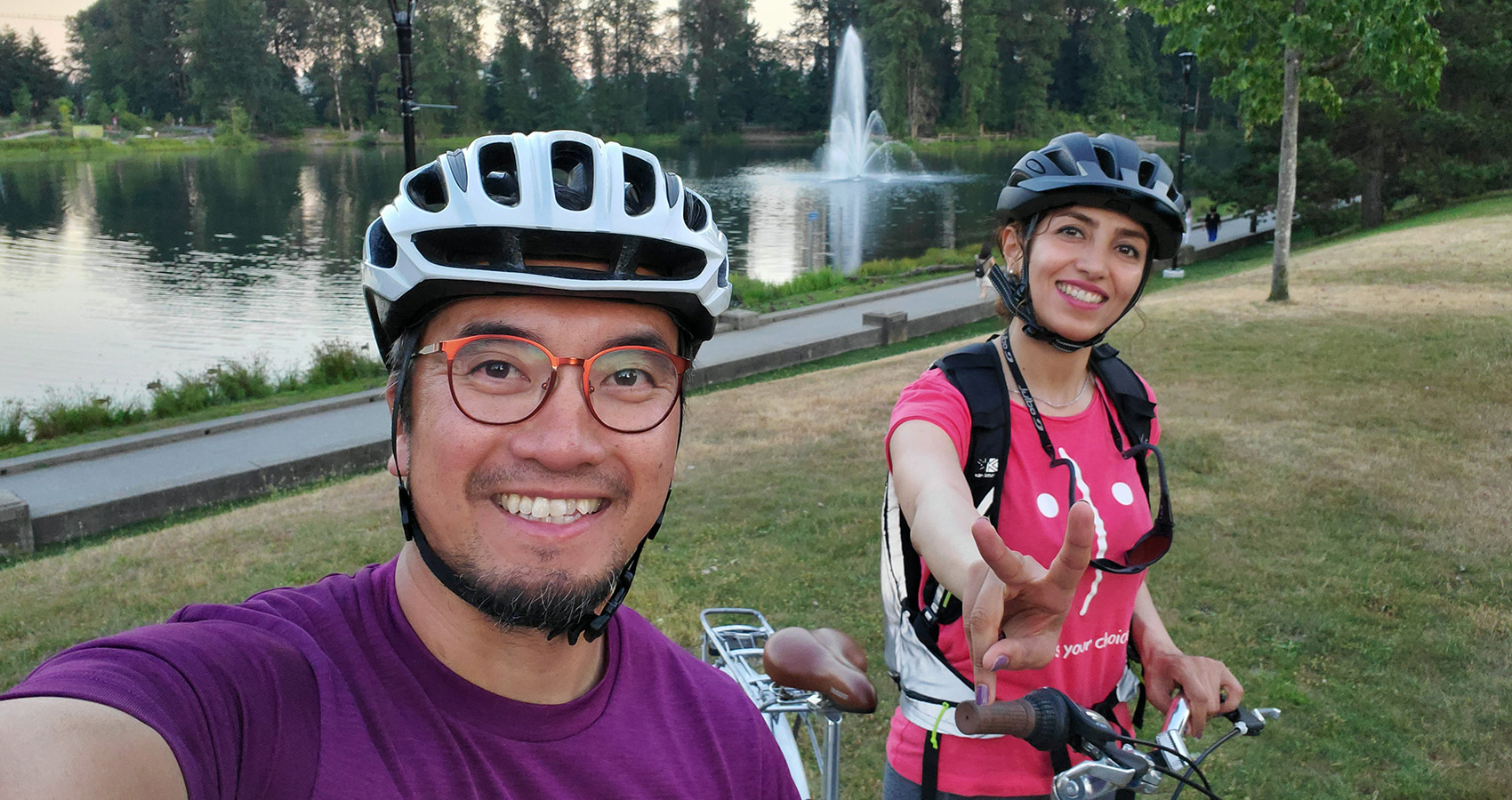 Two people smiling with their bikes in a park