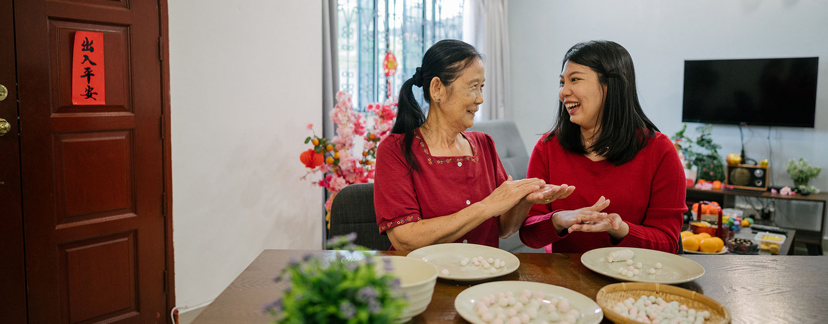 An Asian grandmother and her granddaughter preparing making glutinous rice dumplings for Lunar New Year celebration at home