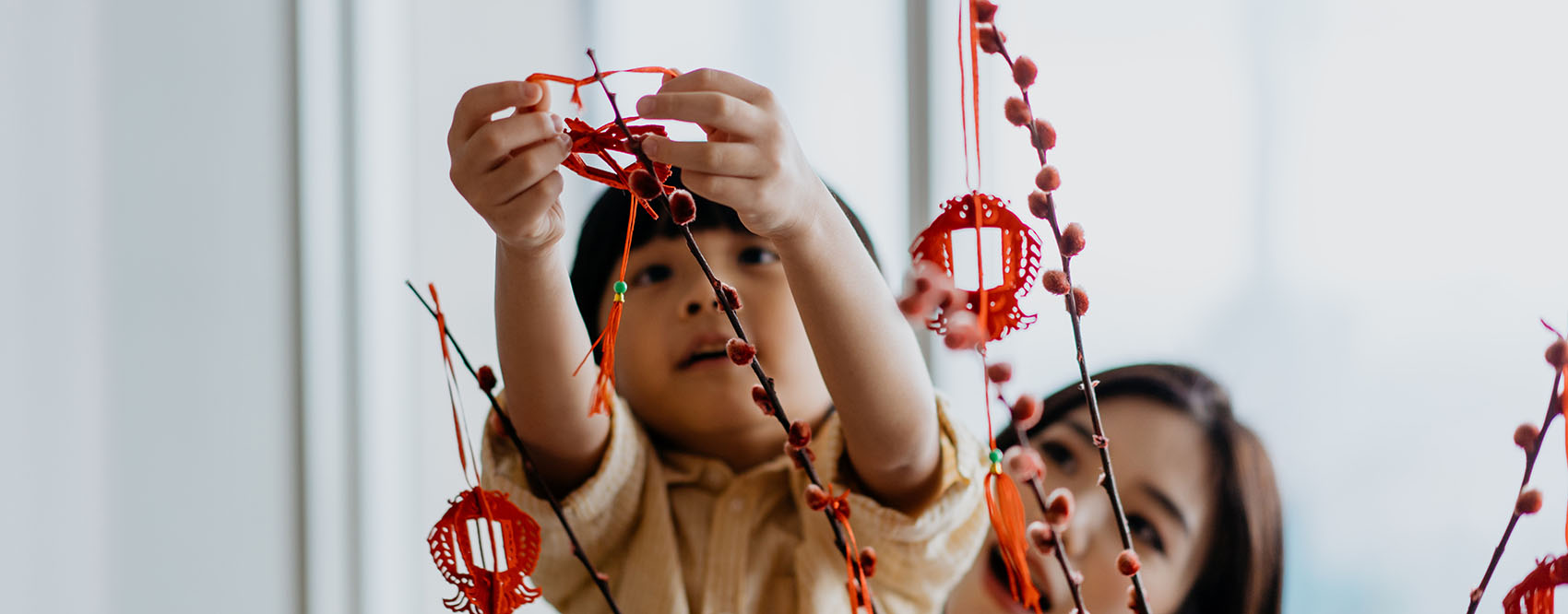 A young boy helping his mother hang Lunar New Year decoration
