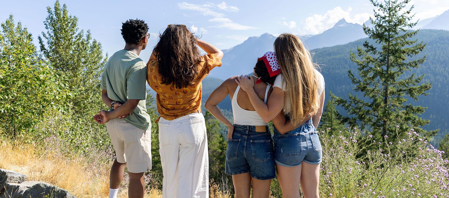 Group of friends standing on wall admiring view with mountains