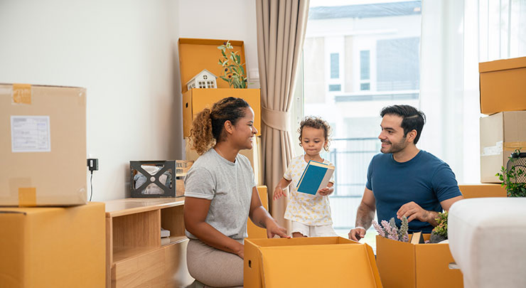 Young family with baby preparing for a house move, packing cardboard boxes
