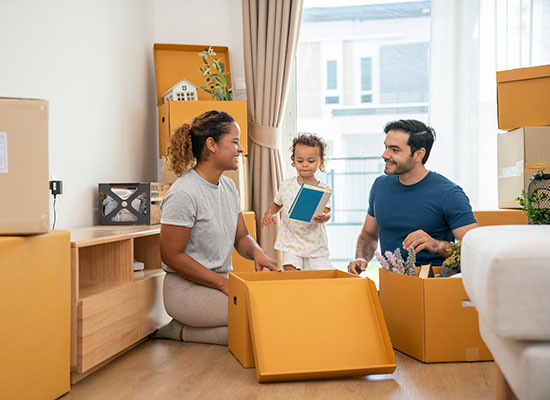 Couple and baby surrounded by moving boxes, preparing to relocate