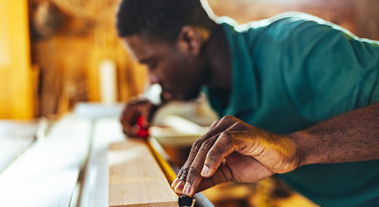 Worker measuring wood before cutting
