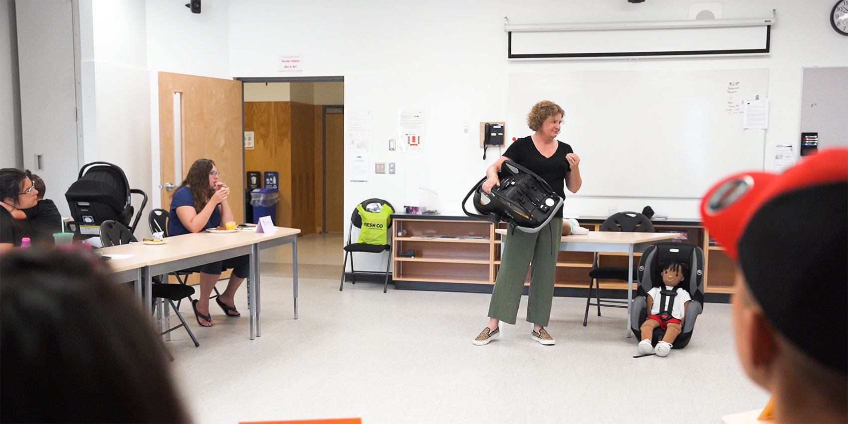 Teacher explaining passenger seat safety to parents in a classroom
