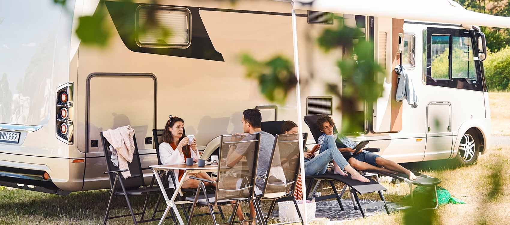 Family relaxing on chairs outside mobile home