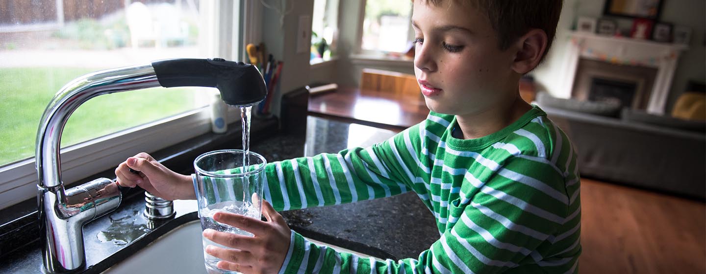 boy filling glass with kitchen sink tap water