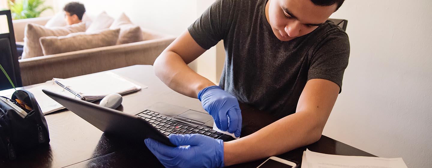 man wearing gloves and cleaning laptop