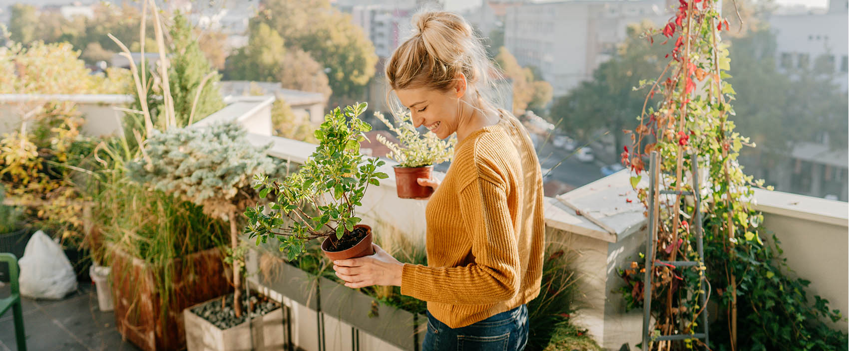 woman holding potted plants on a balcony