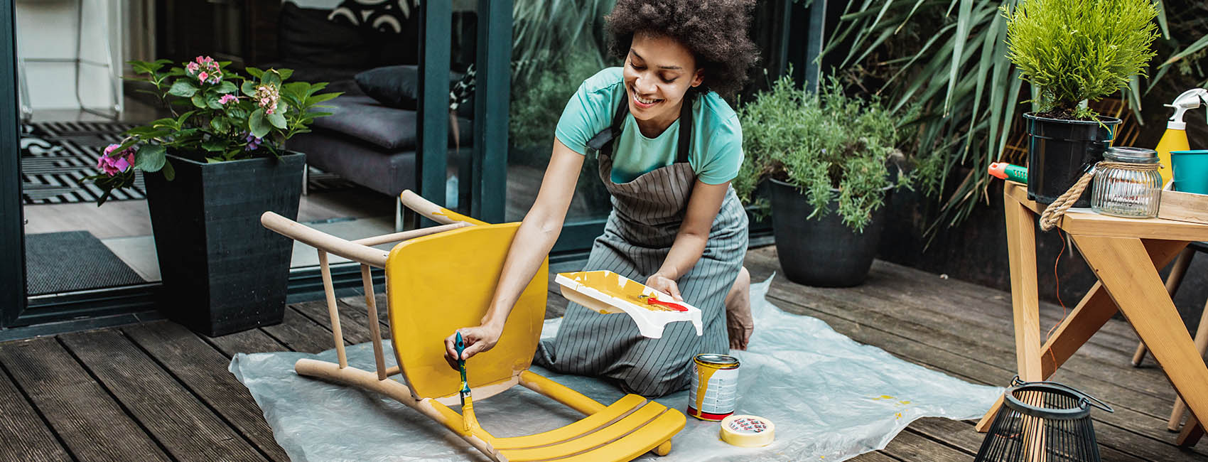 woman painting chair yellow on patio