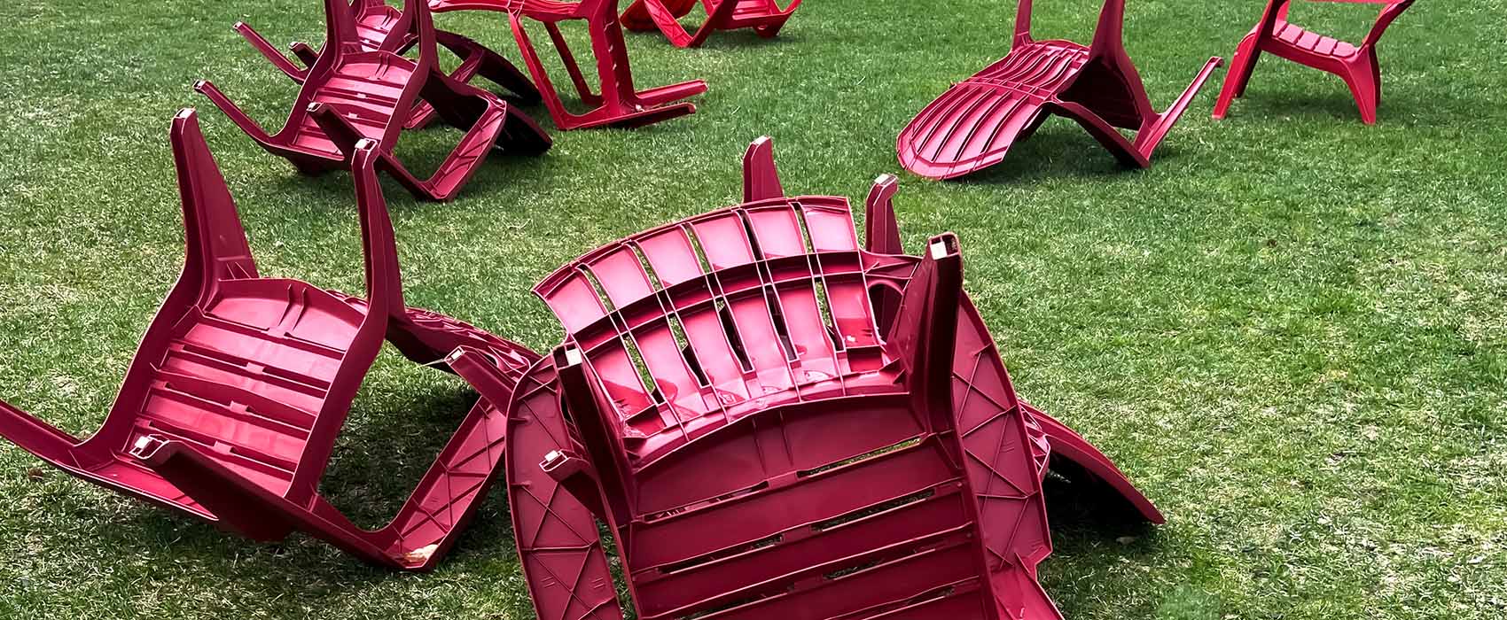 Red lawn chairs overturned on green lawn