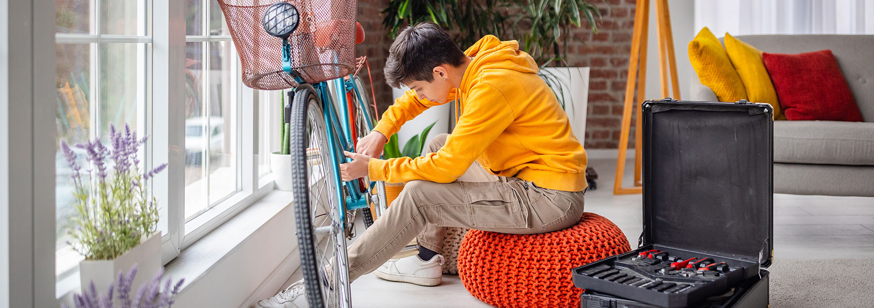 A teenager happily repairing a bicycle at home