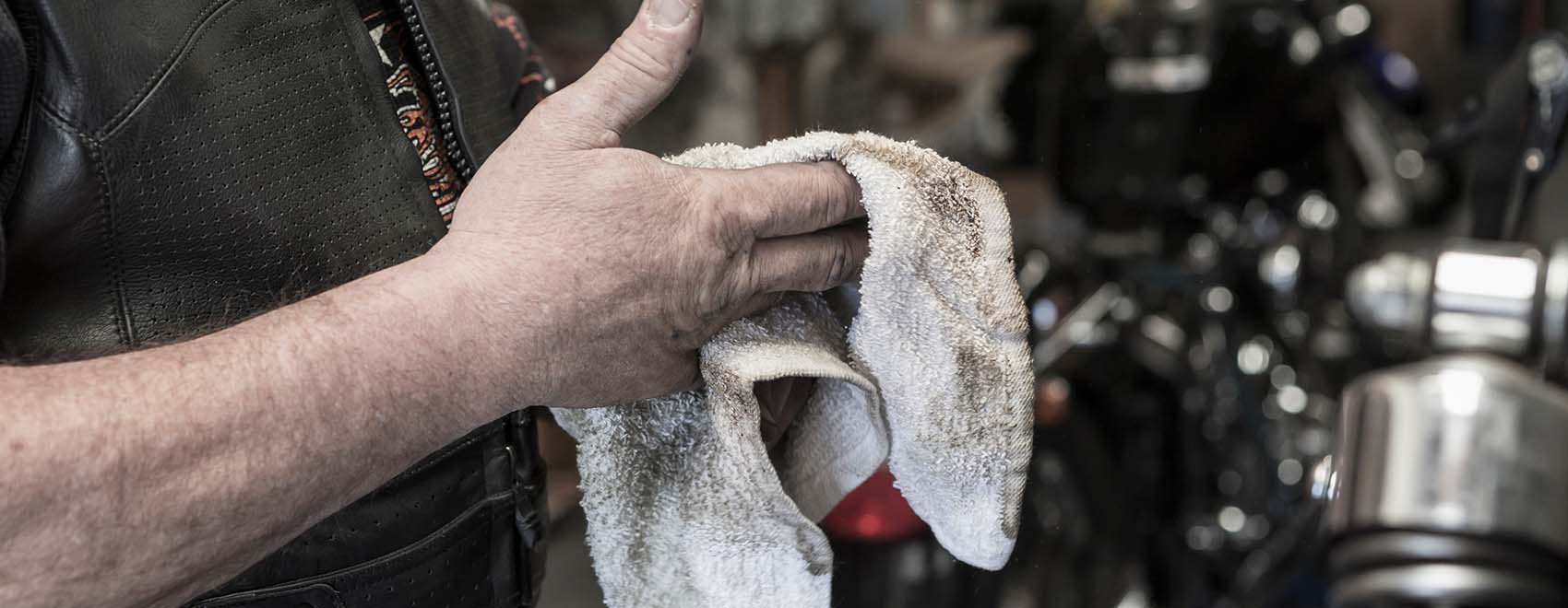man repairing motorcycle wiping hands