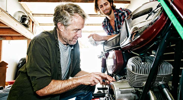 man repairing motorcycle in garage