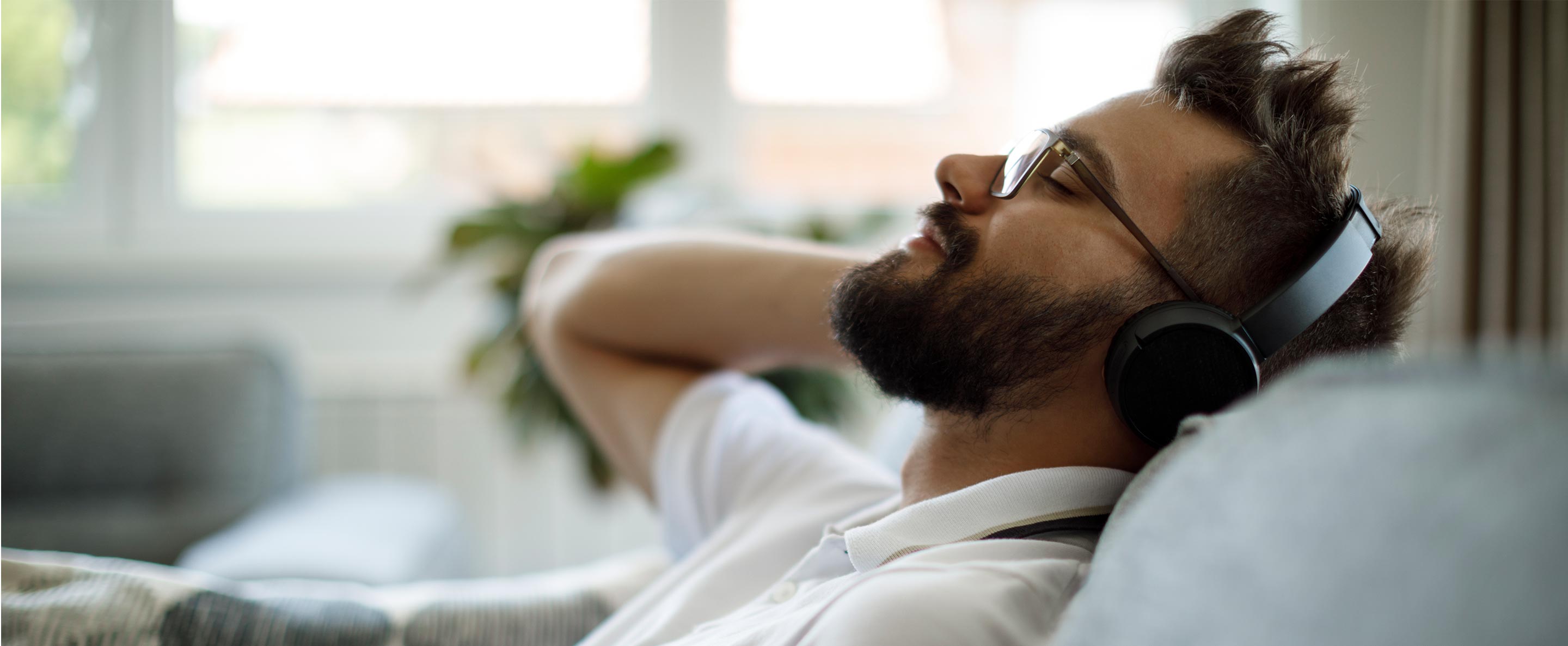 man with bluetooth headphones relaxing on sofa