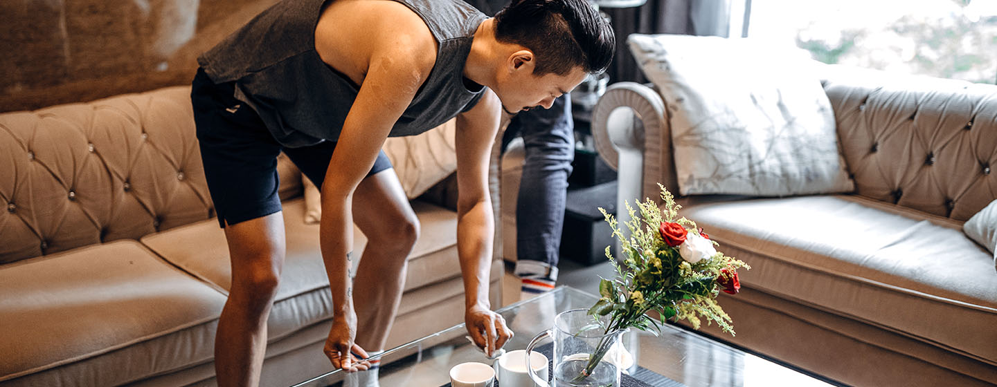 Man cleaning glass top on coffee table