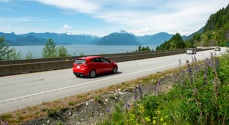Red car traveling on the Sea to Sky Highway in British Columbia