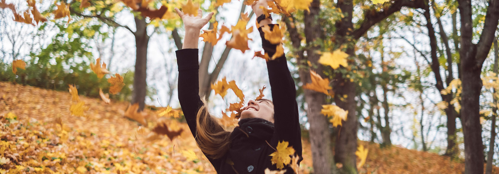 woman playing with falling leaves