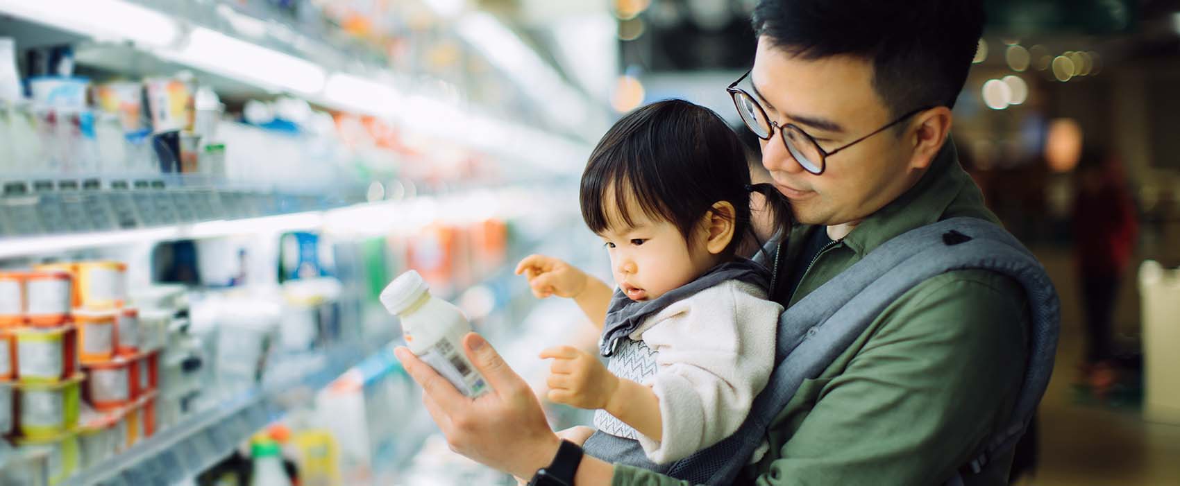 father with daughter grocery shopping for dairy products in supermarket