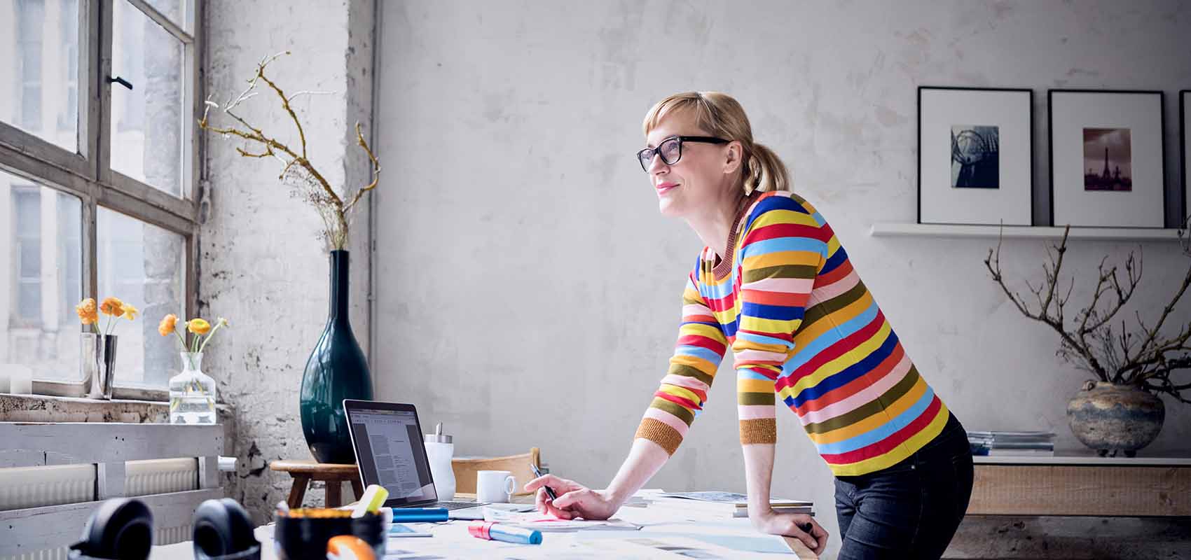  smiling woman standing at desk in a loft looking through window