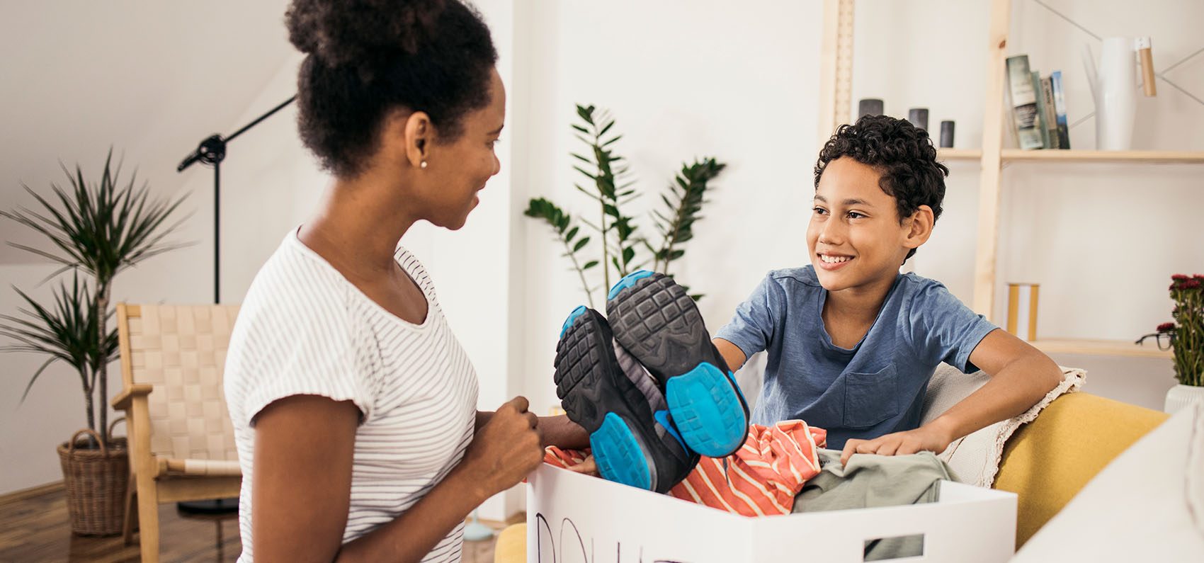 Mother and son preparing a box of clothes for donation