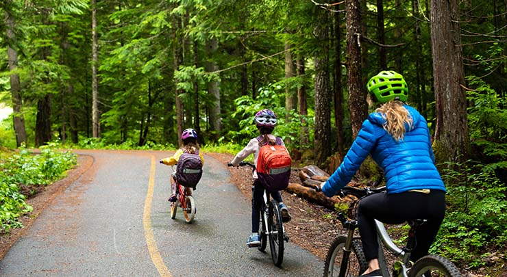 Mom and two kids cycling through forest trail