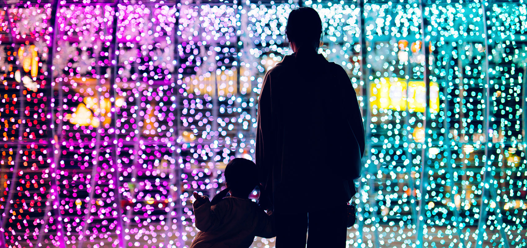 Mother and daughter silhouetted against city bokeh lights