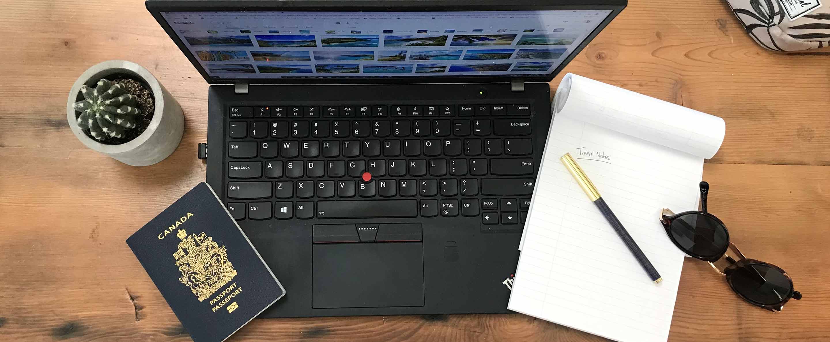 Canadian passport, laptop, and note pad on a table