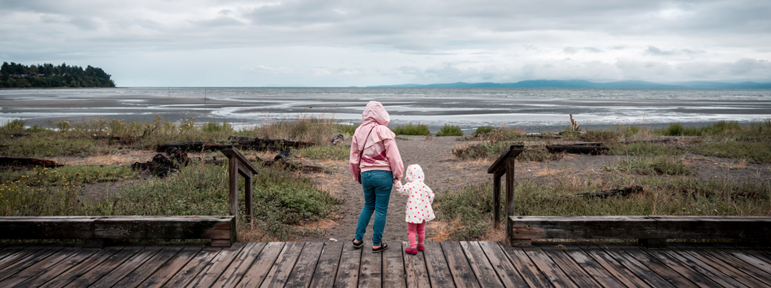 mother and daughter looking out at field and lake