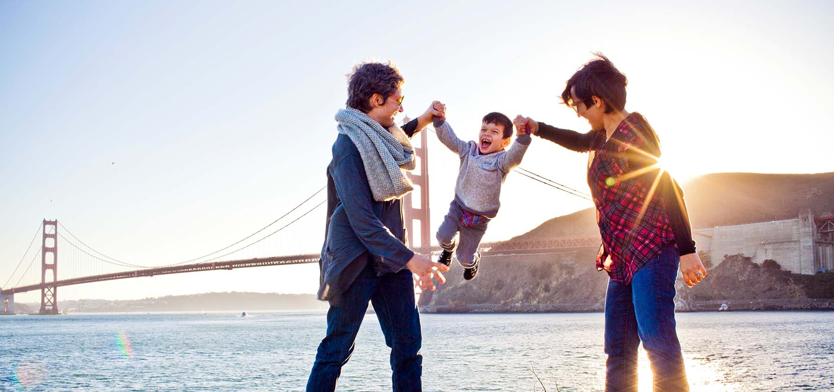 Two moms playing with toddler in front of Golden Gate Bridge, San Francisco, California, USA
