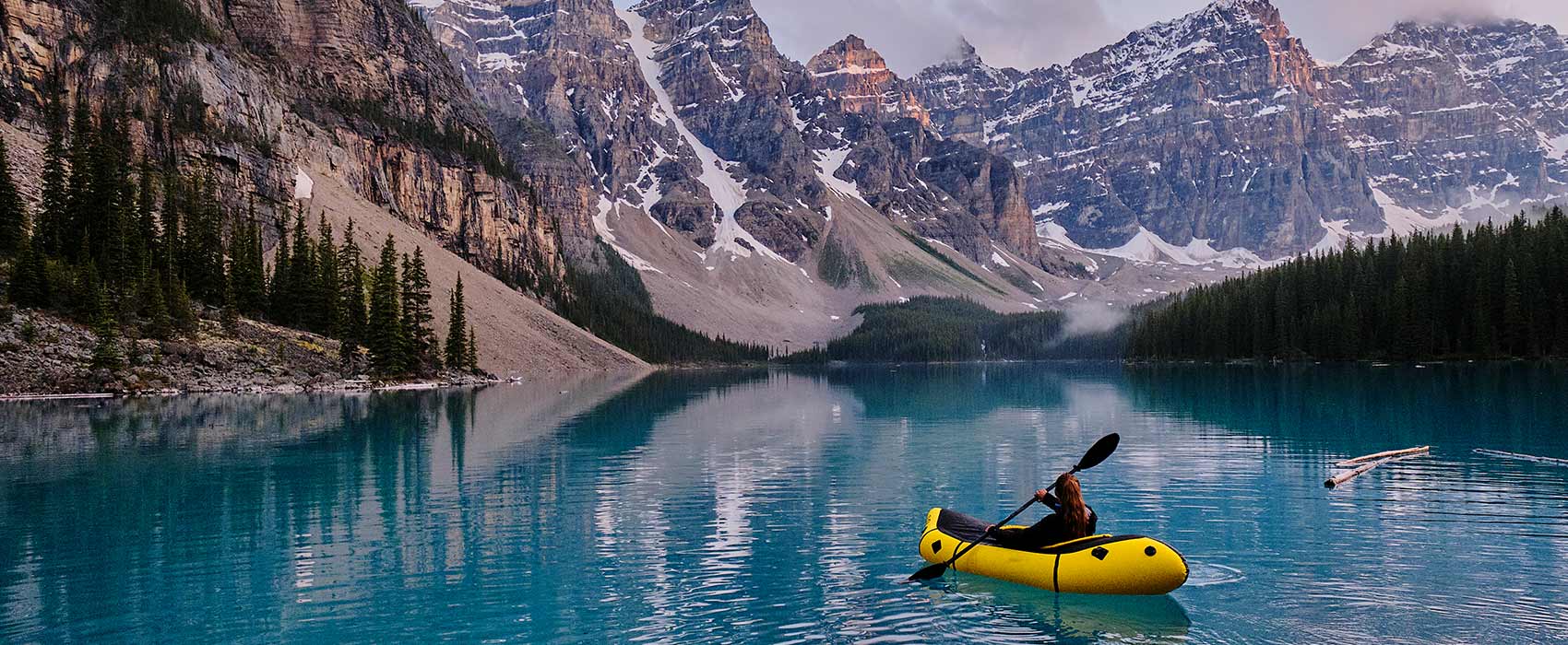kayaking across mountain lake at sunrise