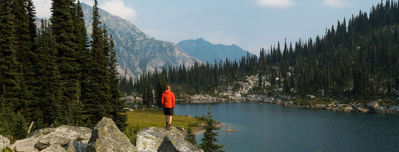 Hiker looks out over a mountain lake