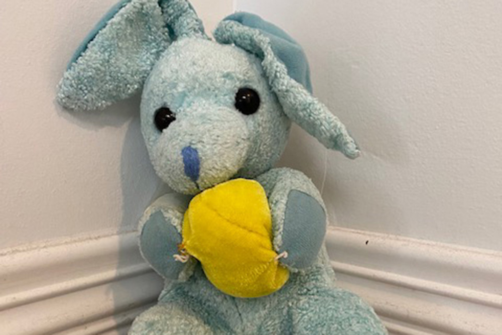 Blue stuffed bunny rabbit holding a yellow plush ball