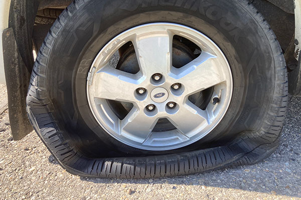 Close up of a flat tire on the road on a sunny day
