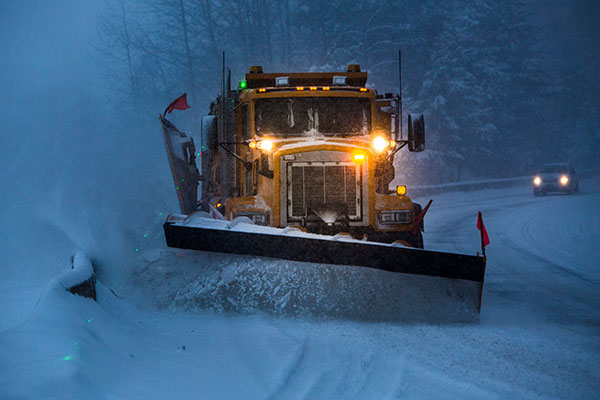 Truck plowing snow off the road at night