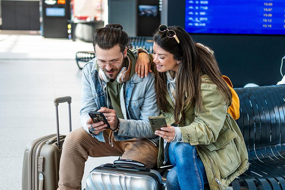 Tourist couple checking their smartphones while at the airport