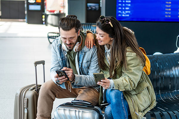 Young couple of tourists using smartphones at the airport