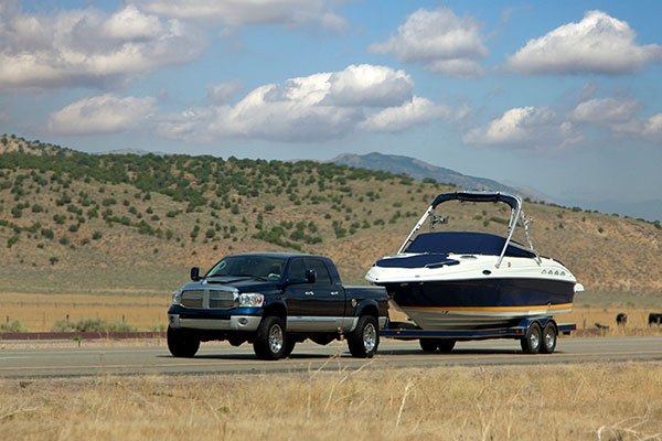 truck tows a boat down a scenic road