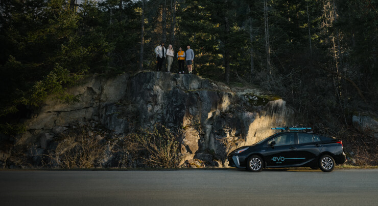 Evo vehicle parked in front of a natural rock face, bathed in soft sunset light