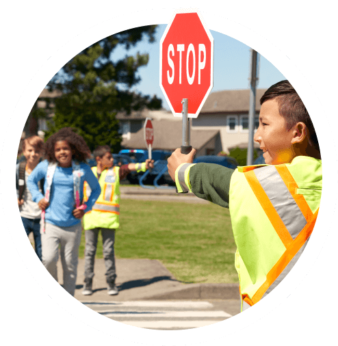Two children holding stop signs while controlling traffic at a school crosswalk