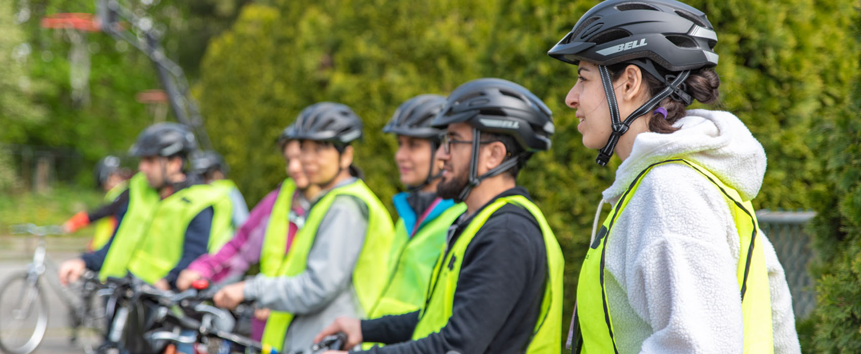 Cyclists in a line wearing helmets and yellow high-vis vests